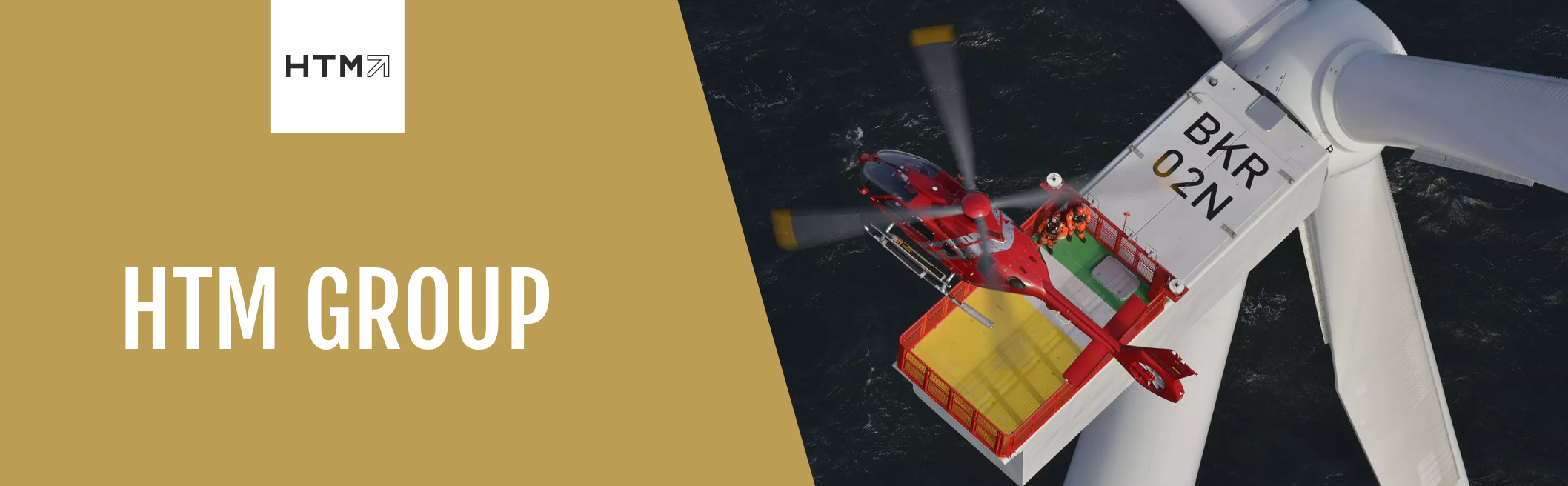 Ein roter Helikopter landet auf einer Plattform oben auf einer Offshore-Windkraftanlage über dem Meer. Zwei Personen in orangefarbener Sicherheitskleidung stehen bereit. Links im Bild das Logo der HTM Group auf goldenem Hintergrund.