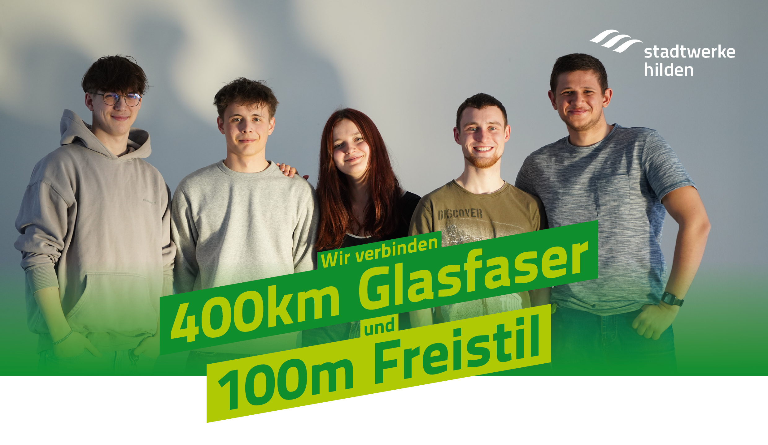 F&uuml;nf junge Erwachsene stehen l&auml;chelnd nebeneinander, dar&uuml;ber das Logo der Stadtwerke Hilden und der gr&uuml;ne Schriftzug: &sbquo;Wir verbinden Wasserwerk und W&auml;rmepumpe&lsquo;.